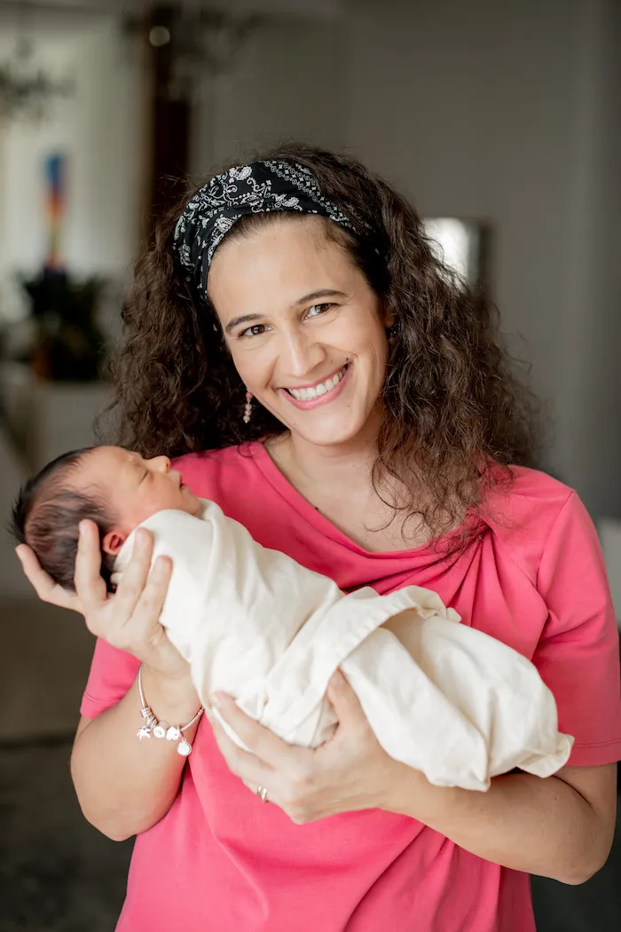 Silvia carrying a baby, and smiling.