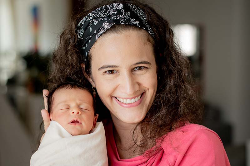 Silvia smiling and carrying a little baby.