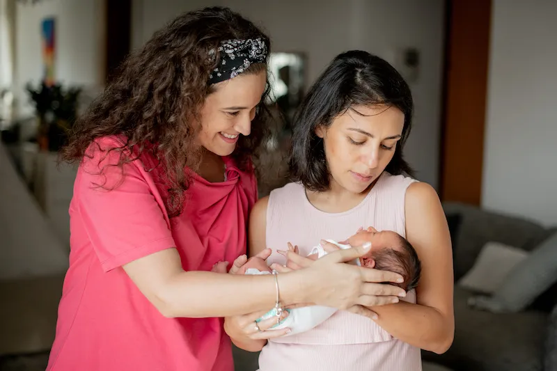 Silvia and a mother both holding her baby.