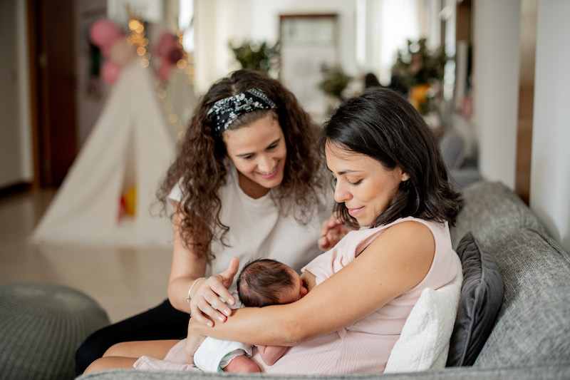 A lactating mother breastfeeding her baby, as Silvia provides support for the baby's head.