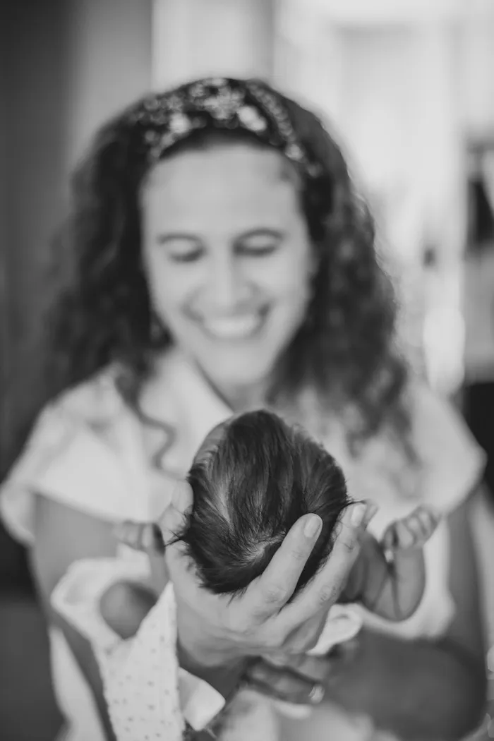 Silvia carrying a baby, with a broad smile on her face.