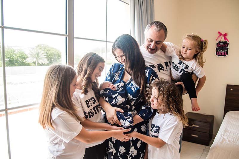 Silvia and her whole family smiling as she carries her baby.