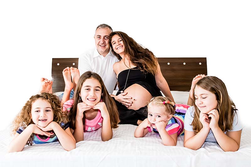 Silvia, her husband and her kids all on a bed and smiling in a group photo.